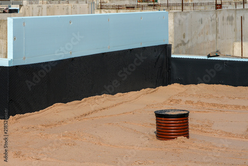 Insulated Concrete Foundation with Drainage Membrane and Utility Well at Building Site