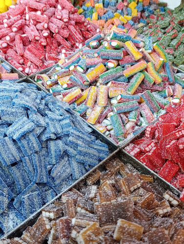 Bulk candy stall at a market shop, colorful loose sweets, gummy candies, sugar snacks, jelly candy and pick-and-mix treats displayed for sale by weight.