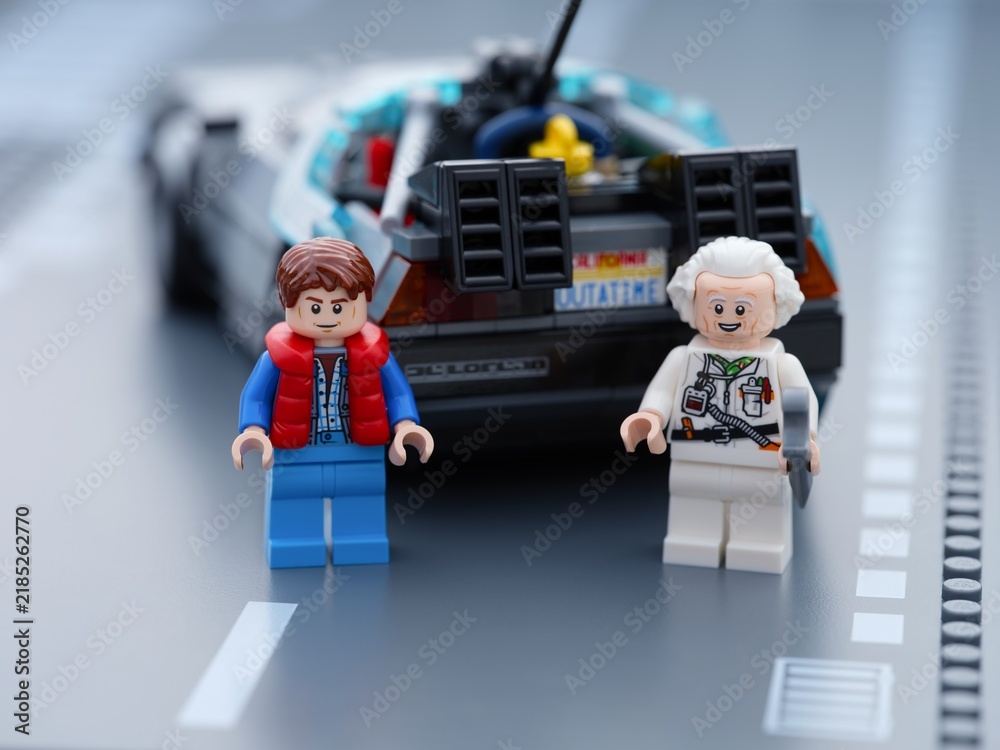 Fototapeta premium Tambov, Russian Federation - June 20, 2026 Lego minifigures of Marty McFly and Doc Brown standing near the back of DeLorean time machine car from Back to the Future on a road baseplate.