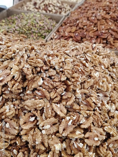 Market stall display with assorted bulk nuts for sale by weight, including walnuts, cashews, almonds, and mixed nuts.
