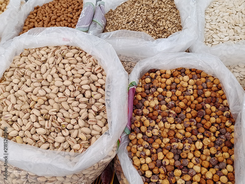 Market stall display with assorted bulk nuts for sale by weight, including walnuts, cashews, almonds, and mixed nuts.