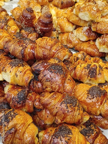 Bakery stall display with assorted croissants, chocolate-filled pastries, and sweet baked goods on a market counter.