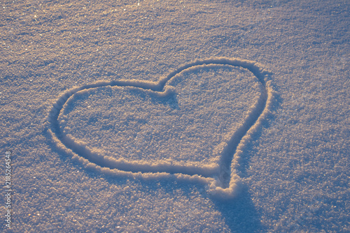 Heart shape drawn in snow on a winter day, creating a romantic scene