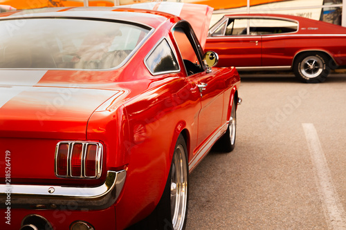 Classic retro red muscle car fastback parked at a car show exhibition during a sunny day, showcasing iconic vintage design, shiny chrome details, and powerful automotive heritage.