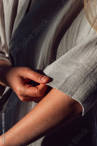 Fotografie Close up of a woman holding the sleeve of a grey linen garment