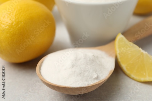 Fotografía Baking soda in spoon and lemons on light grey table, closeup