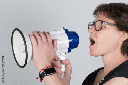 Cuadro en lienzo Adult woman speaking into a megaphone in a studio, representing communication, publicity, announcements and amplified speech