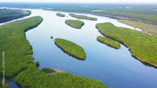 Aerial slow motion pan of river islands drifting through mangrove estuary at sunrise
