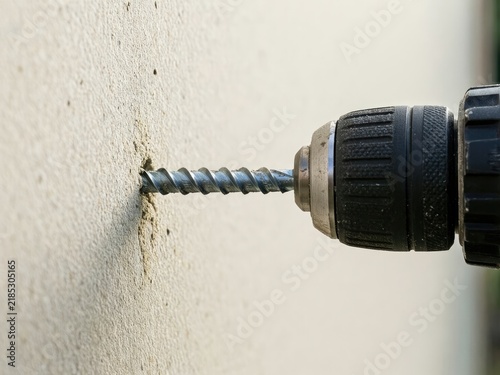 Drill making a hole in a wall at a construction site during daylight hours