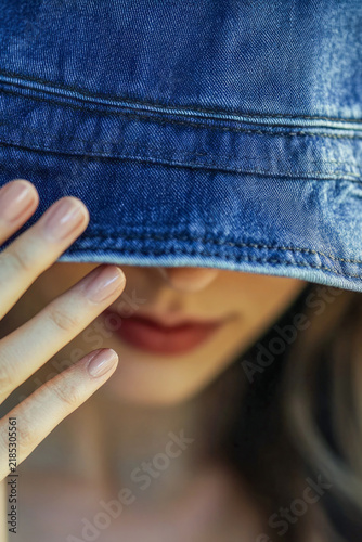 A woman wearing a denim hat to conceal her identity. vertical frame