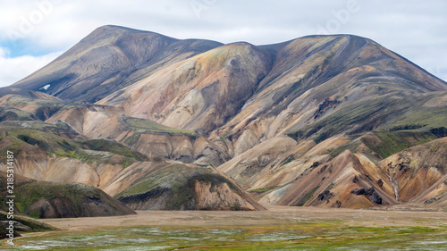 фотографія Vibrant colorful mountains with rainbow-hued layers dominate Landmannalaugar in the Icelandic highlands, with hikers exploring the vast valley below