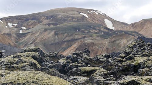 Foto Colorful layered volcanic rock formations across a vast lava field create a striking contrast in the Icelandic highlands