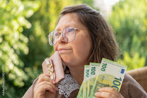 Mature european woman, 50 years old presenting euro banknotes money in her hand, emotional female portrait, financial freedom, cash payments, savings, exchange and cashing currency, real people