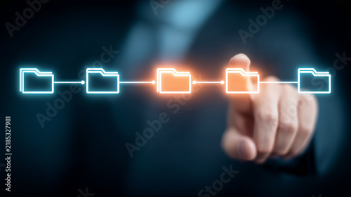A hand selecting connected digital folder icons represents file management document organization and automated information workflow.
