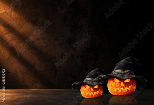 Two carved pumpkins wearing witch hats on dark moody background