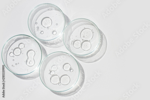 Four Petri dishes with liquid drops and bubbles viewed from above