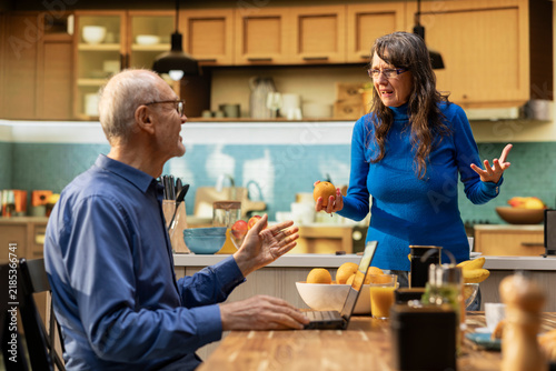 Cuadro en lienzo Older wife and husband argue with visible frustration and rage, showing a troubled moment between a distraught couple facing conflict, unhappiness and relationship difficulties in retirement at home