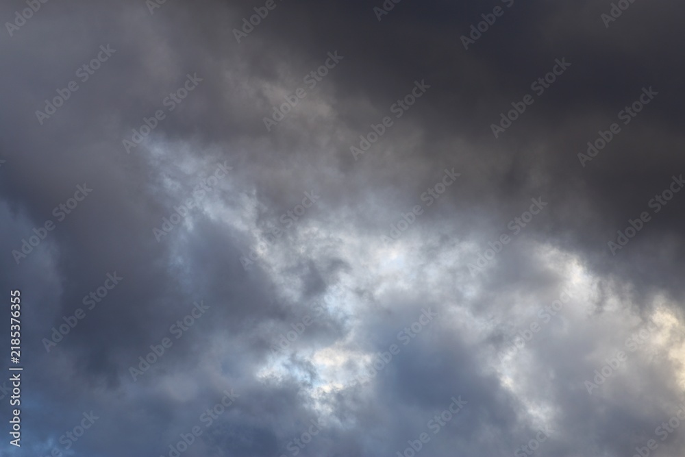 Fototapeta premium Dark storm clouds with light breaking through dramatic overcast sky background