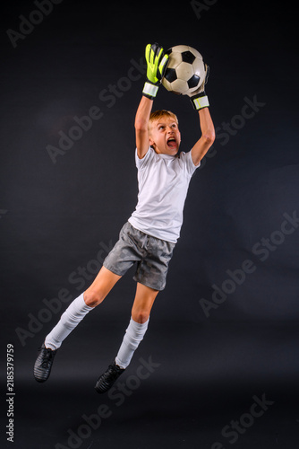 Action shot of a male youth soccer player with goalie gloves leaping to catch soccer ball