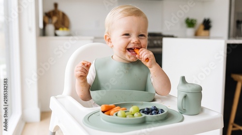 Happy toddler eating fresh vegetables in high chair