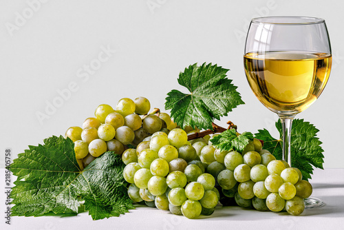 Grapes and glass of white wine on table with green leaves