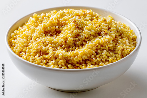 Millet grain served in a white bowl on a plain surface