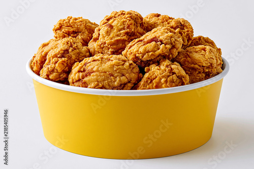 Fried chicken pieces in a yellow bowl on a plain background