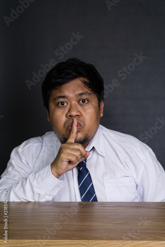Canvas Print A serious young Asian male corporate worker sits attentively at a solid wooden d