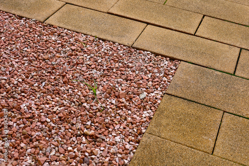 Red crushed rock border next to stone pavement tiles.