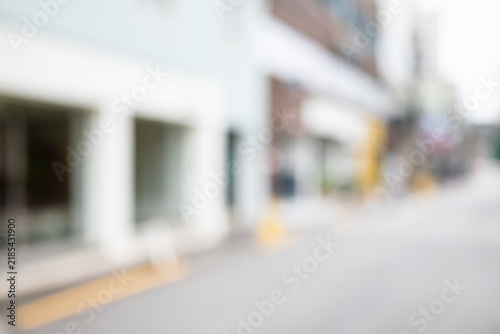 Abstract blurred urban local neighborhood street background with modern white shop storefronts and clear road pavement