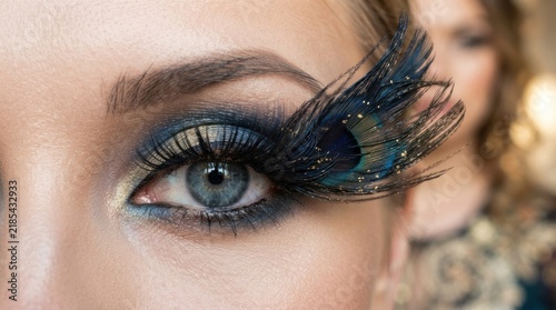 Close up of a woman with dramatic peacock feather false eyelashes and blue eyeshadow.