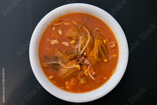 Konstfotografi Red Asian noodle soup with vegetables served in a round white bowl on a contrasting black background