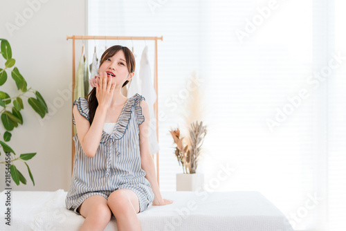 Obraz na plátne 朝のベッドで眠そうにぼんやりする若い女性・寝起きや睡眠不足をイメージする朝時間
