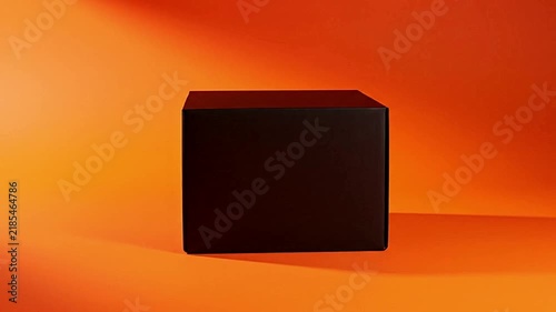 Black square box rotating smoothly against vibrant orange studio background in this seamless motion video clip