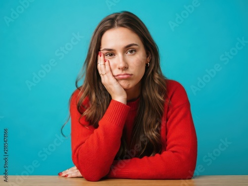 Bored young woman resting head on hand looking at camera