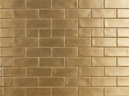Glossy gold subway tile wall texture with geometric pattern.