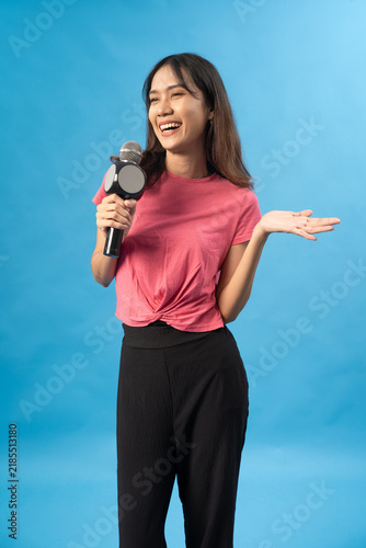 Smiling Woman Holding Microphone and Presenting with Open Hand