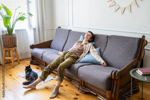 Obraz na płótnie Exhausted zoomer woman rests motionless on sofa at home with eyes closed and arms hanging loosely