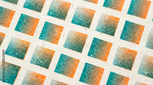 Abstract background with a repetitive pattern of orange and turquoise gradient squares printed on a rough paper texture