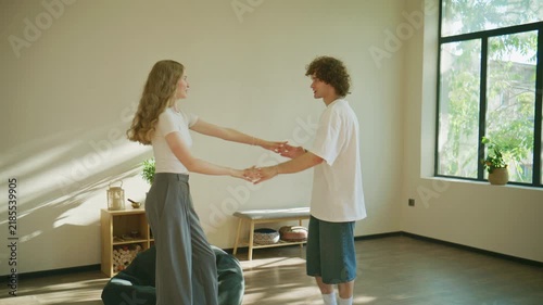 Couple dances in a bright room with large windows filled with sunlight during afternoon hours