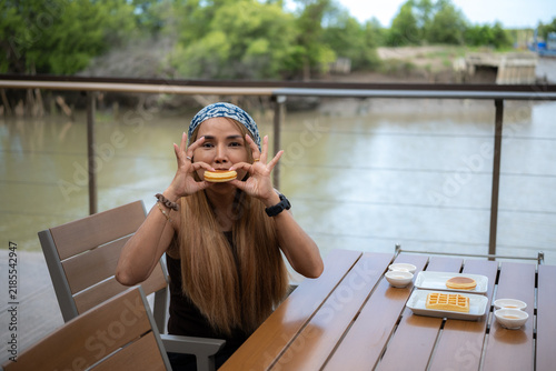 A woman is eating pancakes by the river.