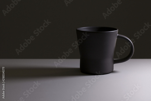 Matte ceramic coffee cup in dramatic light on dark background, morning ritual concept