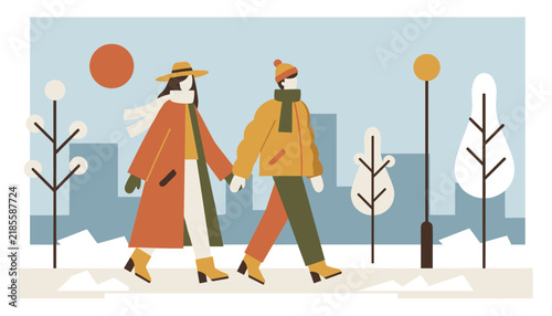 Romantic couple holding hands and walking together in a snowy city park during winter with tall skyscrapers behind.