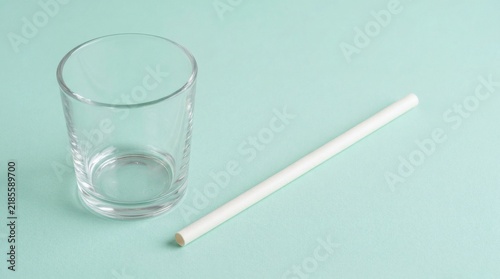 Eco-friendly biodegradable paper straw with minimalist glass on pastel mint background. Sustainable drinking accessories, zero waste lifestyle, natural texture, clean composition.