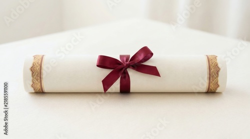 Elegant rolled diploma or certificate with red satin bow, formal education achievement document, academic graduation concept, celebratory reward scroll