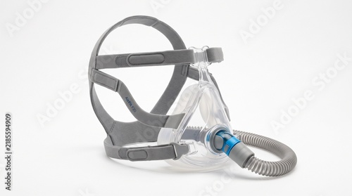 Medical CPAP respiratory mask with flexible corrugated breathing tube and grey headgear isolated on white background