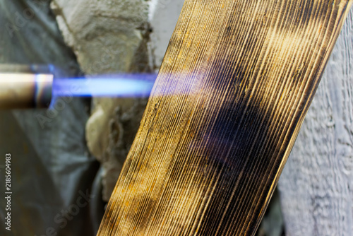 Obraz na płótnie Close-up of a gas torch flame charring a wooden board to create a rustic texture