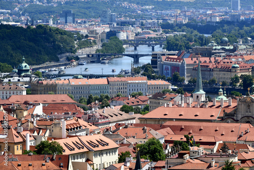 Cuadro en lienzo A high-angle view overlooking red roofs toward the Vltava River and its stone bridges spanning across the city under bright daylight in Prague