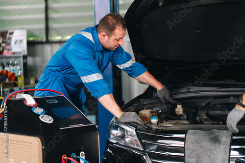Ev car battery cells service Automotive mechanic inspecting vehicle engine with diagnostic equipment during professional service and maintenance work indoors