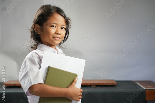 Konstfotografi Young schoolgirl holding books in classroom